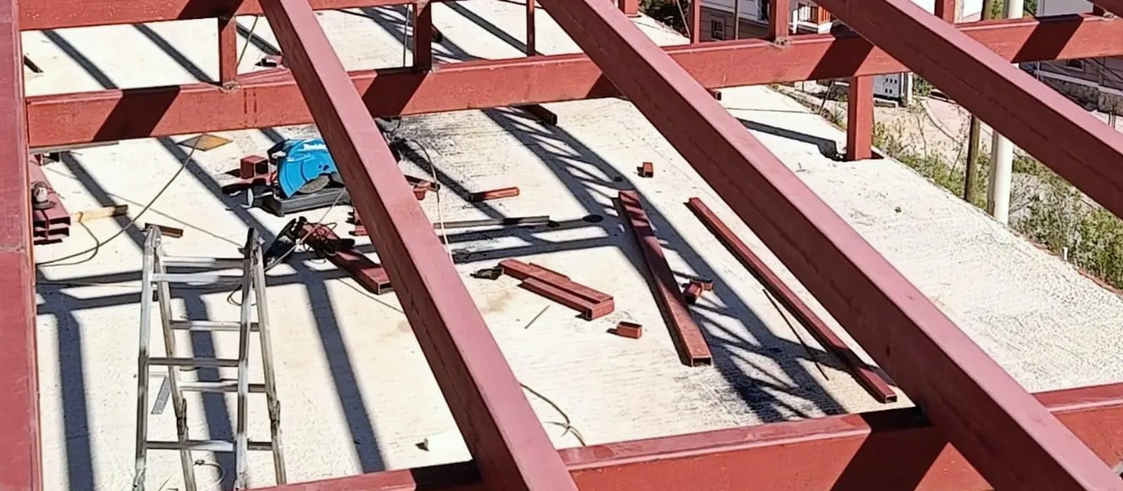 Bordo boyalı çelik kirişler beton döşemenin üzerine yan yana oturtulmuş, aralarında merdiven duruyor