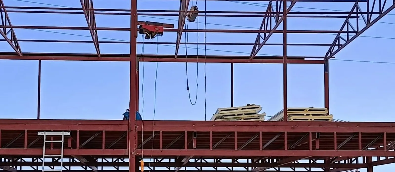 Gökyüzüne karşı duran çelik kolonlar ve üstlerine oturtulmuş makas sırası