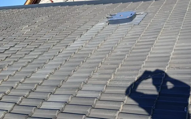 Eğimli kiremit yüzeyin ortasına oturtulmuş küçük metal havalandırma kapağı