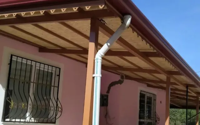 Saçak altında sıralanan ahşap mertekler ve duvar boyunca aşağı inen yağmur borusu