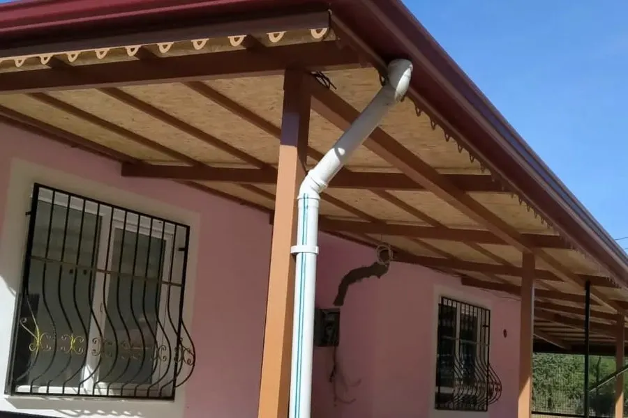 Saçak altında sıralanan ahşap mertekler ve duvar boyunca aşağı inen yağmur borusu