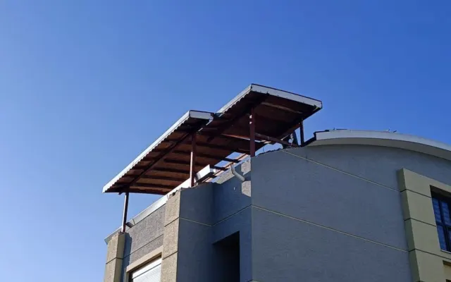 Yuvarlak köşeli bir yapının teras katına kurulmuş çelik taşıyıcılı örtü