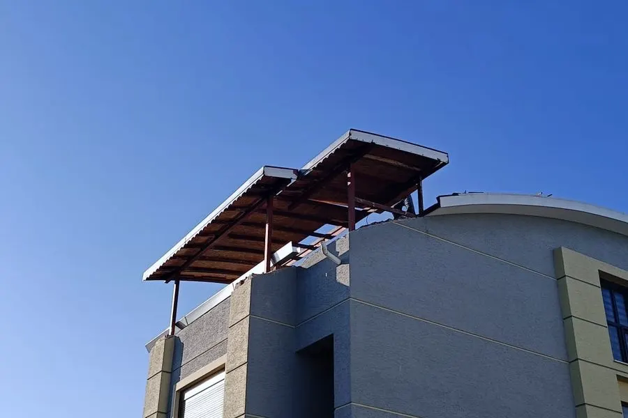 Yuvarlak köşeli bir yapının teras katına kurulmuş çelik taşıyıcılı örtü