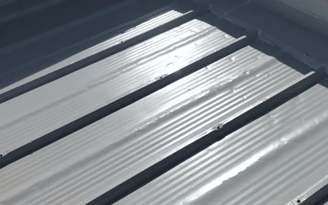 Gri metal çatı panellerinin mahya boyunca birleştiği nokta ve vida sıraları